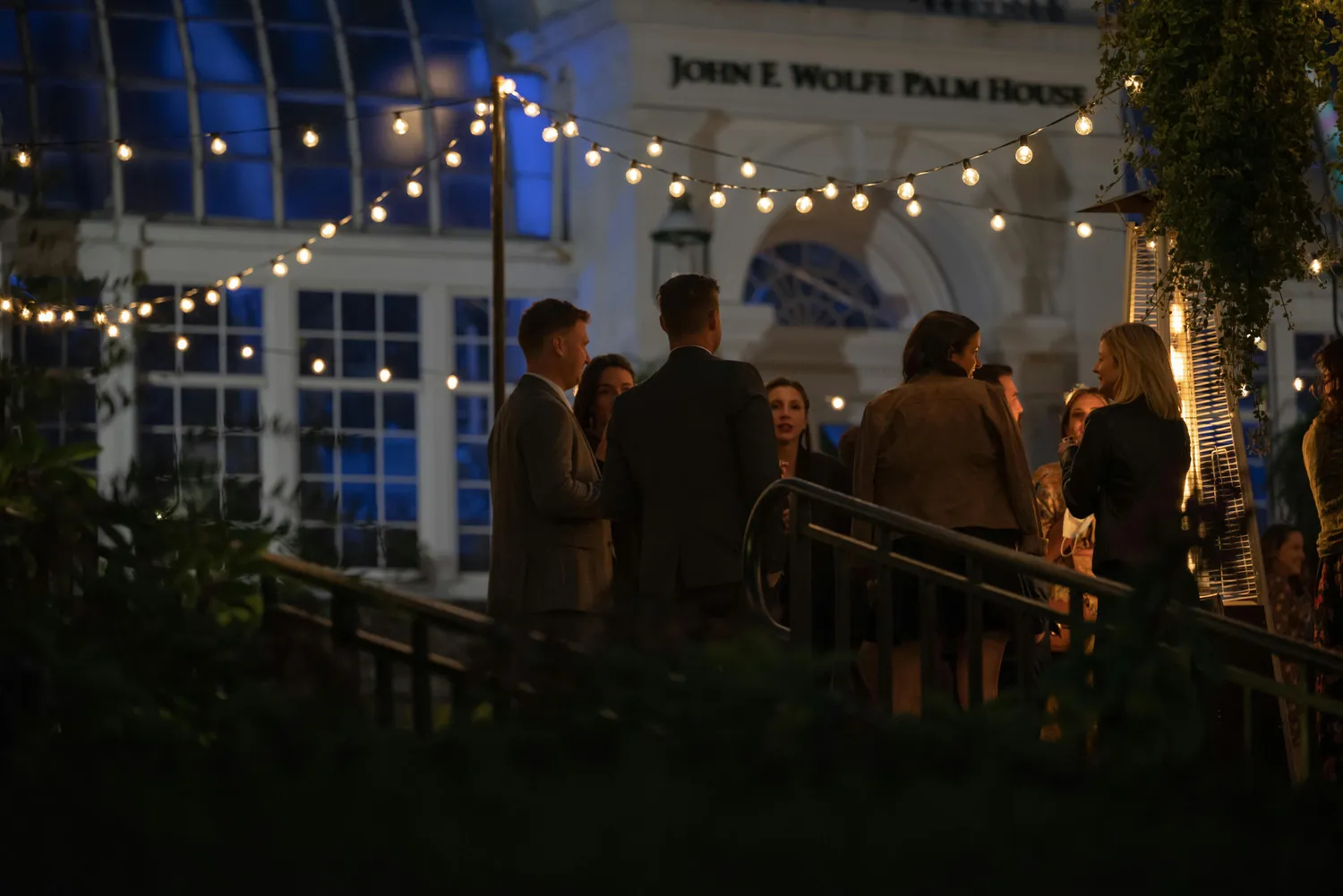 Friends enjoying an outdoor evening gathering with string lights.